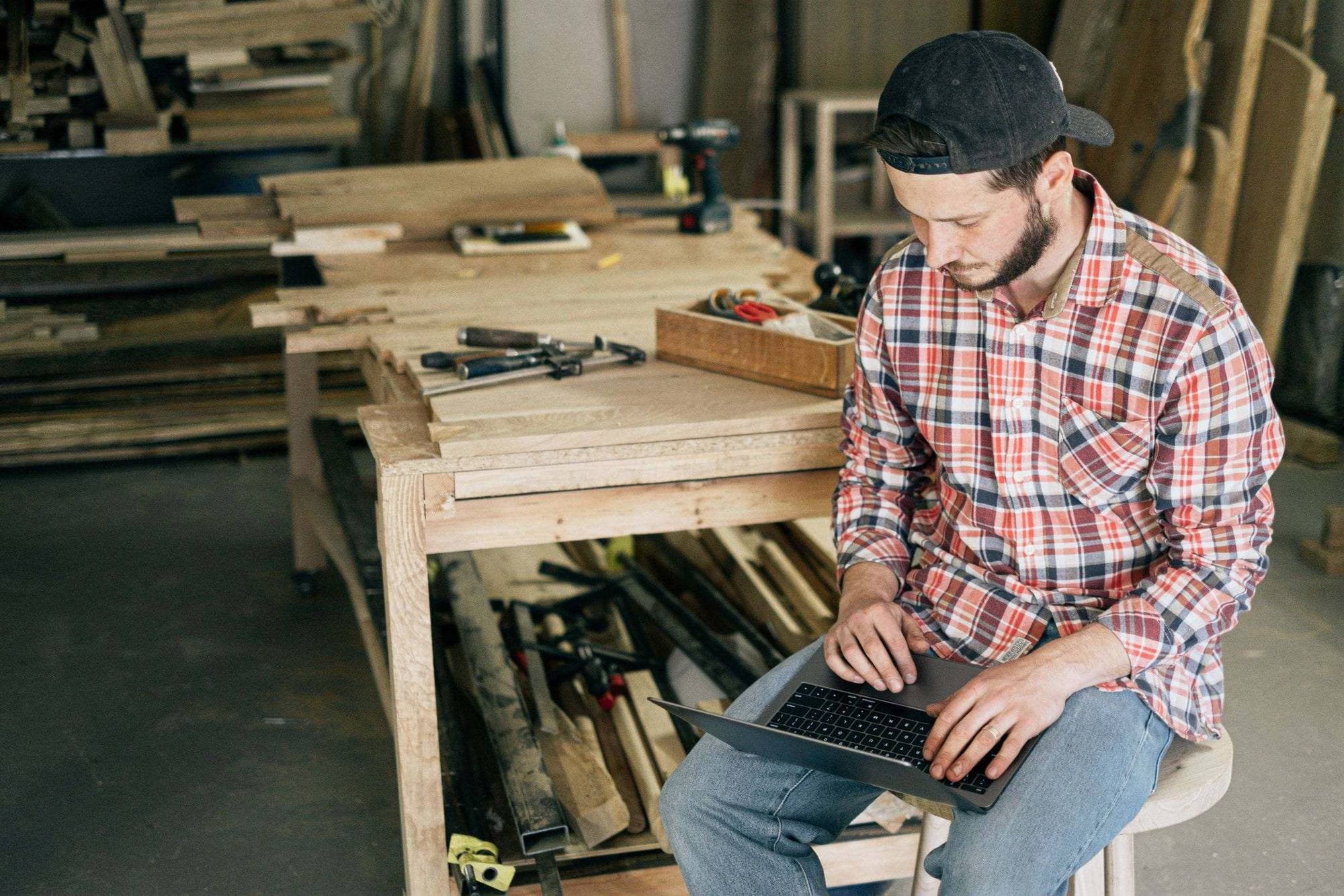 A carpenter working on a laptop in his woodshop