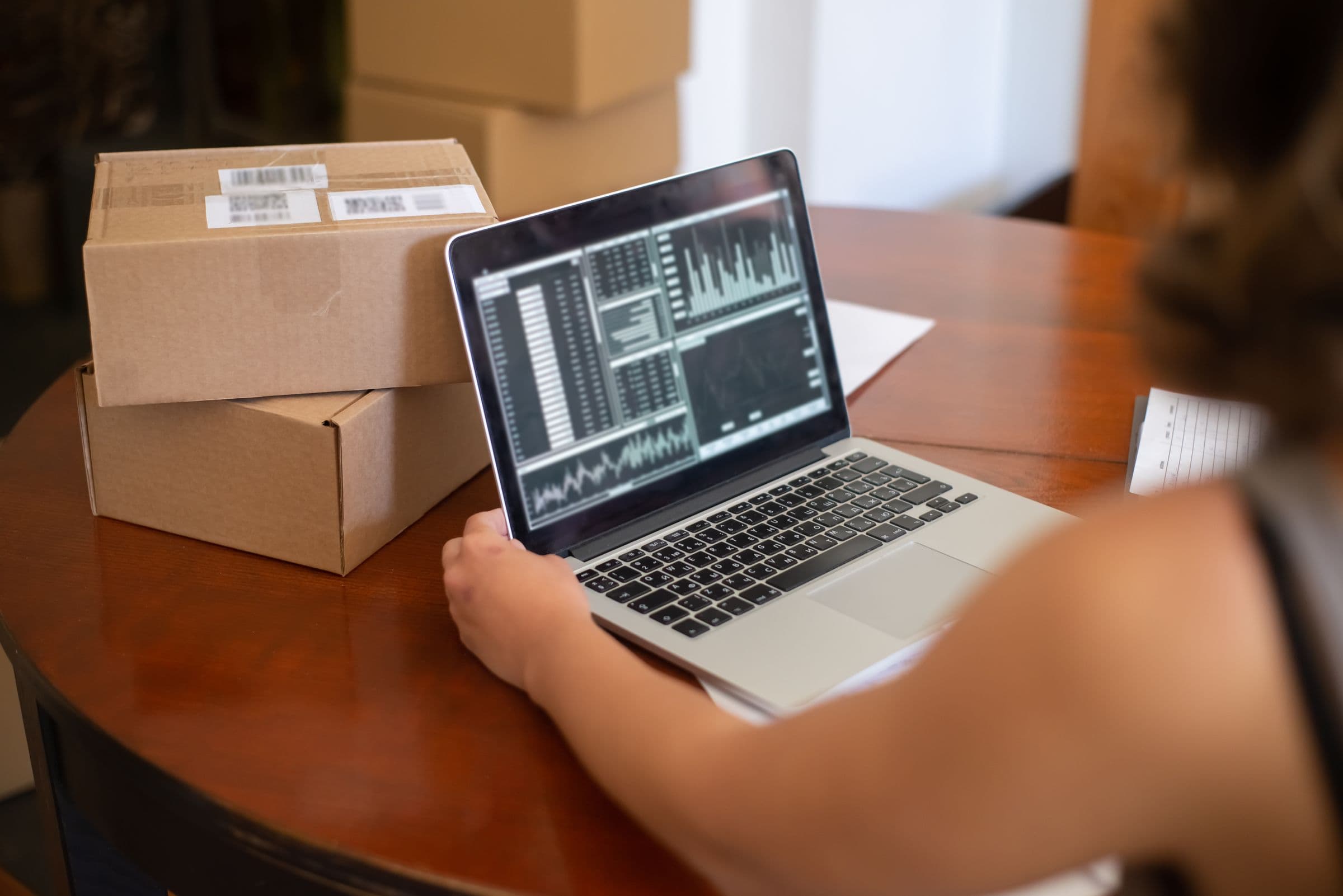 A laptop showing store analytics on a desk among shipping boxes